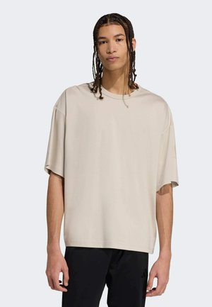 Beige oversized t-shirt gemaakt van zachte stof, met een ronde hals en korte mouwen. Eenvoudig ontwerp zonder zichtbare patronen of accenten.