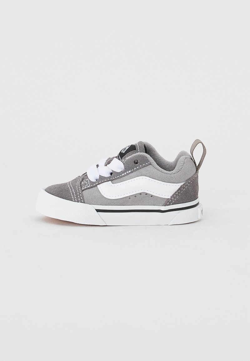 Graue Wildledersneaker für Kleinkinder mit weißen Schnürsenkeln und seitlichem Streifen, ausgestattet mit einer Gummisohle und gepolstertem Schaft für Komfort. Schwarzes Logo auf der Zunge.