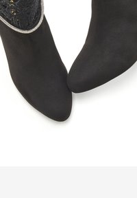 Botas de ante negras hasta el tobillo con punta afilada y una parte superior de encaje texturizado, que cuentan con un acento decorativo de cuentas en la abertura.