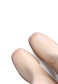 Μπεζ δερμάτινες μποτές μέχρι τον αστράγαλο με στρογγυλή μύτη, λεία υφή, ραφές στο πλάι και χαμηλού προφίλ καουτσούκ σόλα, προβαλλόμενες από πάνω.