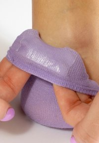 Calzino viola con testo nella zona del tallone, polsino elastico liscio e design aderente. Mano che tiene il calzino vicino alla zona del tallone.