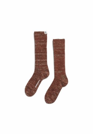 Paar lange, gerippte, braune melierte Socken mit kleinem weißem Etikett an einem Bündchen und weißem Text auf einer Sohle vor weißem Hintergrund.