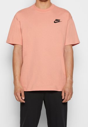 Camiseta de algodón rosa con cuello redondo y mangas cortas, con el logo negro de Nike en la parte izquierda del pecho.