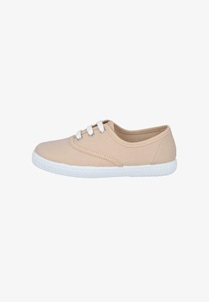 Zapatilla baja de lona beige con cordones blancos y suela de goma blanca texturizada, mostrada de perfil sobre fondo blanco.