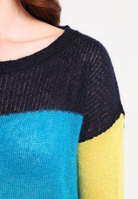 Stickad pullover med rund halsringning. Har färgblockering i marinblått, teal och gult. Lättviktig, texturerad tyg med lös passform.