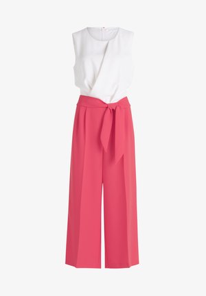 Top bianco senza maniche con un design drappeggiato, abbinato a pantaloni rosa a vita alta e gamba ampia con fiocco anteriore e texture liscia.