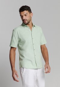 Korte mouwen blouse van lichtgroene stof met een button-down kraag en een voorkant met knopen, met subtiele textuur en ergonomische pasvorm details.