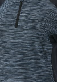 En enfärgad lättviktig atletisk pullover med kvartslång dragkedja, som har ett strukturerat grått och blått horisontellt randmönster.