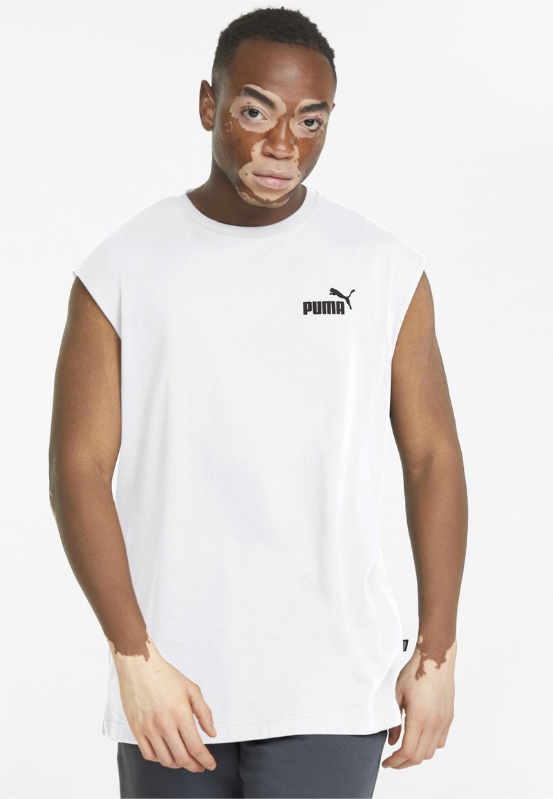 Hvid ærmeløs t-shirt lavet af bomuld, med et sort Puma-logo på venstre bryst. Glat tekstur, afslappet pasform, korte sideslids.
