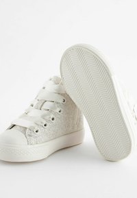 Vita hög-top sneakers med ett glittrande tygöverdrag, platta vita snören och en texturerad gummisula med ett fiskbensmönster.