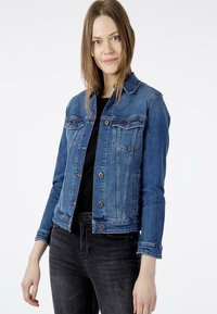 Jeansowa kurtka w średnim niebieskim kolorze z klasycznym wzornictwem, zapinana na guziki, z dwiema kieszeniami na piersi. Ma długie rękawy i lekko skrócony fason.