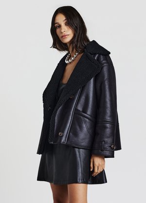 Giacca di pelle nera con collo in shearling, dotata di un design doppiopetto, due tasche frontali e una vestibilità leggermente cropped.