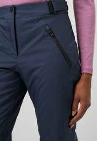 Navy blue pants with a sleek design, featuring a zipper pocket, belt loops, and a smooth, textured fabric. Close-up of waist and side.
