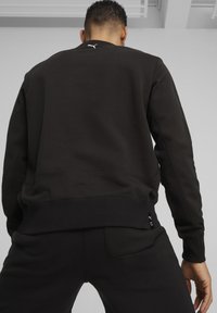 Felpa nera con polsini e orlo a coste, con un piccolo logo bianco sul retro del collo. Tessuto liscio e design dal fit casual.
