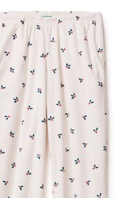 Pantaloni del pigiama leggeri color crema con una fascia elastica in vita, caratterizzati da un motivo ripetuto di agrifoglio in verde scuro e rosso. Tessuto dalla consistenza morbida.