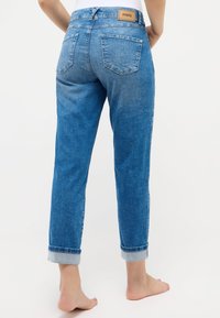Hoch geschnittene blaue Jeans aus Denim mit heller Waschung, umgeschlagenen Säumen, zwei Gesäßtaschen und einem braunen Lederetikett am Taillenbund.