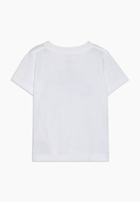 Maglietta bianca in cotone con maniche corte, collo tondo e schiena liscia. Tessuto morbido, senza motivi né accessori visibili.