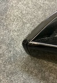 Gros plan d'un arrache-agrafes en plastique noir avec un bord usé sur une surface texturée grise.
