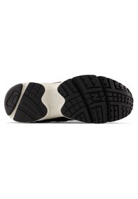 Black rubber sole with pronounced treads and patterns; features beige midsole and embossed logo; suitable for various surfaces and activities.