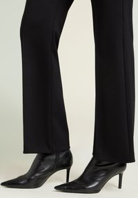 Zwarte enkellaarsjes met spits toelopende neuzen, hoge naaldhakken, gemaakt van glad leer, met een strak ontwerp en minimale hardware.