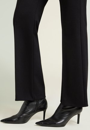 Schwarze Stiefeletten mit spitzen Zehen, hohen Stiletto-Absätzen, aus glattem Leder, mit einem schlanken Design und minimaler Hardware.