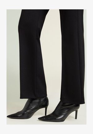 Zwarte enkellaarsjes met spits toelopende neuzen, hoge naaldhakken, gemaakt van glad leer, met een strak ontwerp en minimale hardware.
