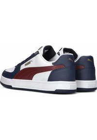 Baskets Puma avec une combinaison de couleurs blanche, marine et bordeaux. Présentent un cuir lisse, un col rembourré et un accent notable en or sur le logo.