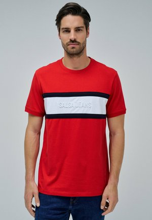 Camiseta de algodón roja con una franja central blanca con el texto en relieve "SALSA JEANS," bordeada por franjas en azul marino. Cuello redondo y mangas cortas.
