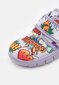 Μωβ και λευκό ύφασμα παπούτσι με πολύχρωμο εκτυπωμένο σχέδιο κόμικ με φράσεις και γραφικά. Κλείσιμο με βέλκρο και υφή σόλας.