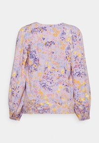 Blouse florale lilas à manches longues, présentant un motif coloré de fleurs jaunes et violettes, des poignets froncés et un pli discret au dos.