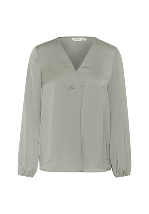 Gaišpelēka, garām piedurknēm blūze ar V veida kakla izgriezumu un savelktiem aproces, ar gludu satīna tekstūru un apjoza dizainu.