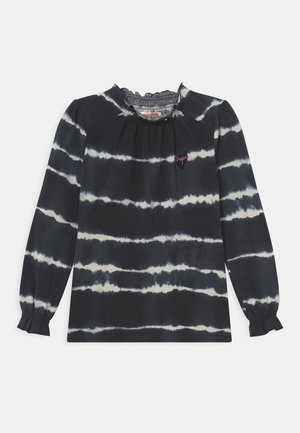 Langærmet sort top med hvide vandrette tie-dye striber, flæset krave og manchetter samt en lille hjerteformet lap på brystet.