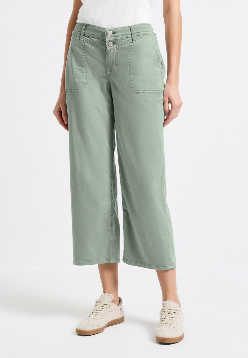 Pantalones de pierna ancha verde claro, hechos de un tejido suave, con dos bolsillos frontales, cierre de doble botón y detalles de costura visibles.