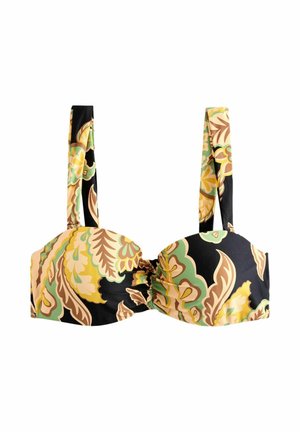 Donna che cammina all'aperto indossando un crop top floreale nero e giallo abbinato e pantaloni a gamba larga con infradito e gioielli d'oro.