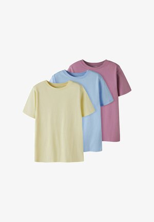 Trois T-shirts unis à manches courtes dans des tons pastel jaune pâle, bleu clair et rose poudré, présentés en chevauchement sur un fond blanc.