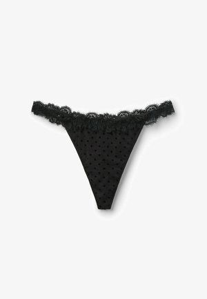 Black thong underwear featuring a polka dot pattern and a lace trim along the waistband. Made of sheer material with a tapered back.