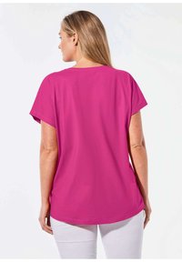 Fuchsia t-shirt met korte mouwen, een relaxte pasvorm, ronde halslijn en een gladde katoentextuur, gecombineerd met witte broek.