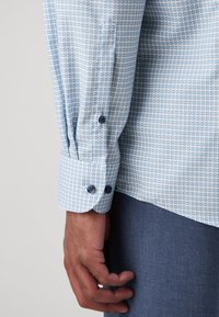 Blauw geblokte blouse met lange mouwen van zachte katoen. Bevat ronde manchetten met donkerblauwe knopen en een ontspannen pasvorm.