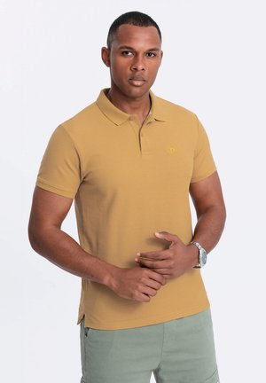 Sennepsgul polo t-shirt med klassisk krave, korte ærmer og slids ved siderne. Har broderet logo i matchende gult.