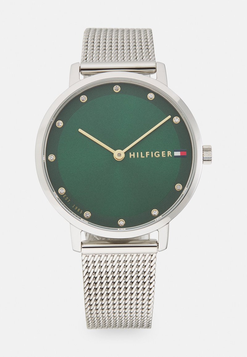 Zöld analóg óra ezüst szövött szíjjal, minimalista dizájnnal, arany mutatókkal és strasszkövekkel jelölt sima számlappal.