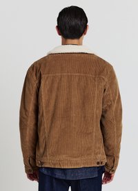 Braune Cordjacke mit einem weißen Schafslederkragen, im lässigen Schnitt, mit vertikal gerippter Textur und Druckknopfakzenten am Saum.