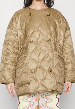 Personne portant une veste matelassée oversized marron clair avec de gros boutons et un pantalon à motifs avec des lignes ondulées multicolores.