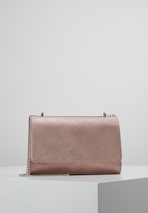 Pochette rectangulaire métallique rose avec fermeture à rabat et bandoulière en chaîne argentée posée sur un socle blanc devant un fond gris uni.