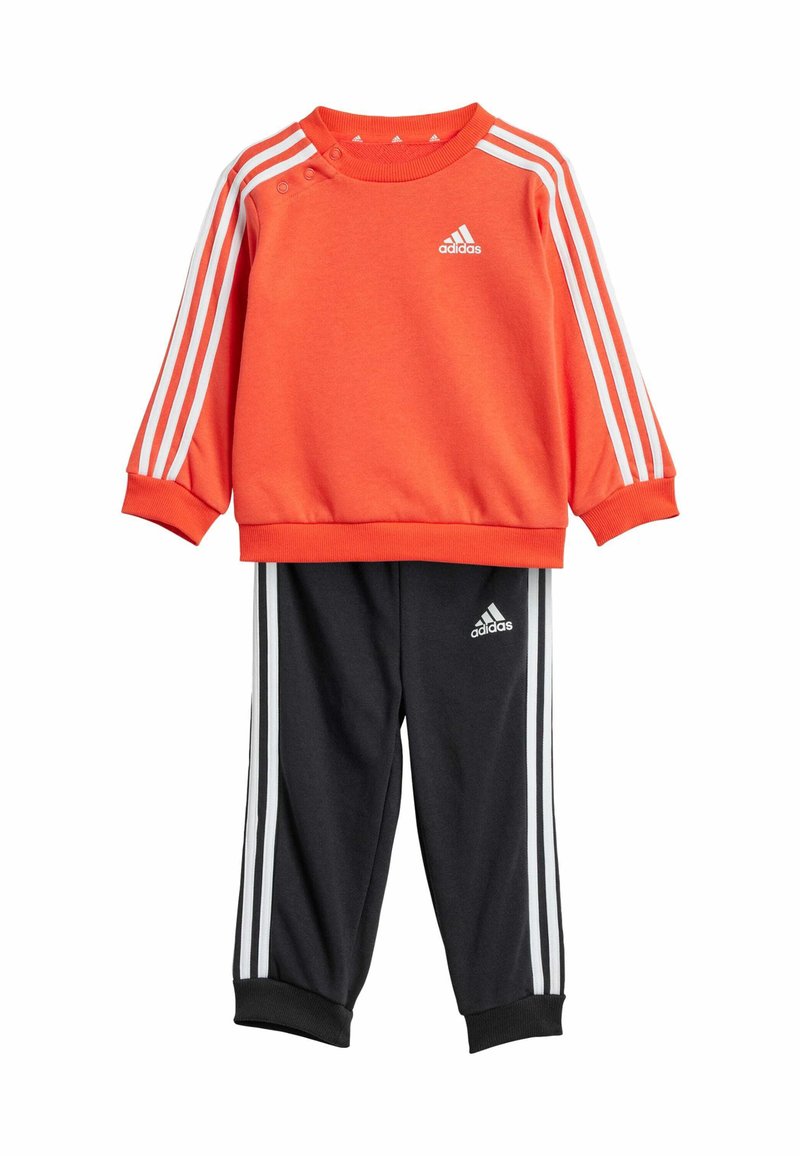 Felpa arancione con strisce bianche e logo, abbinata a pantaloni neri con strisce bianche e logo, entrambi realizzati in tessuto morbido.