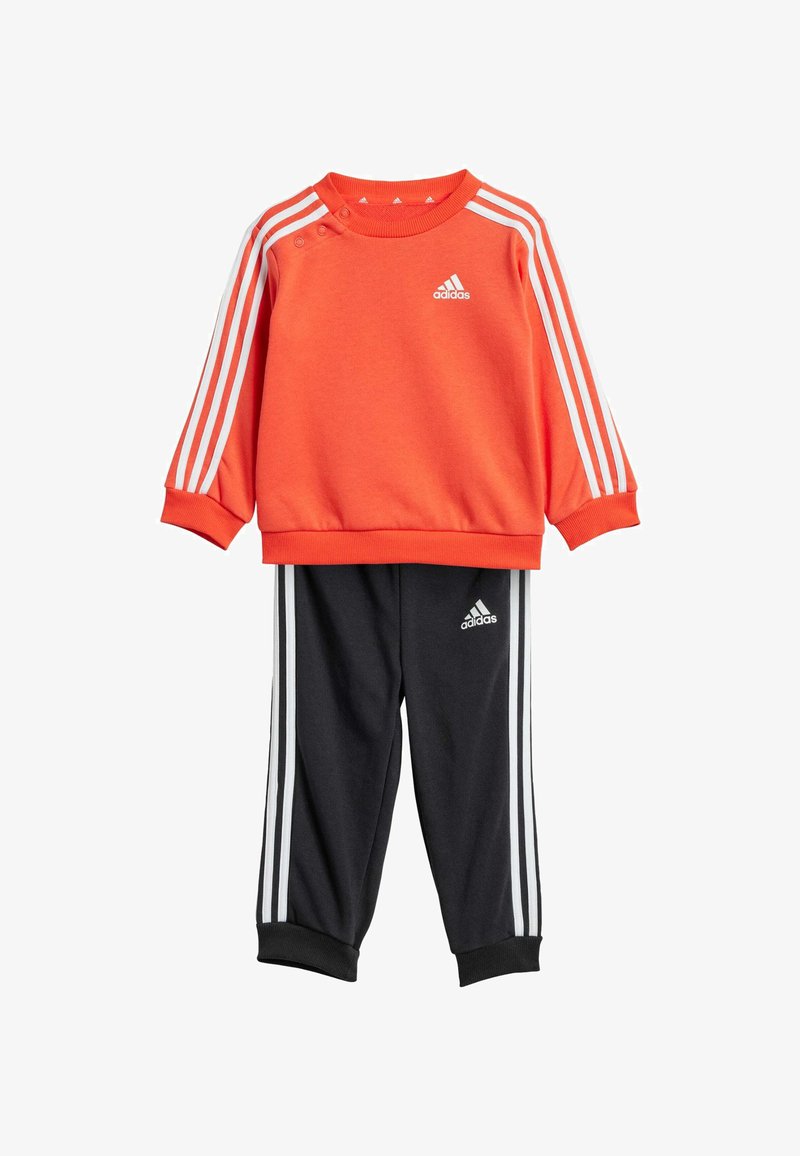 Sudadera naranja con franjas y logotipo blancos, combinada con pantalones negros con franjas y logotipo blancos, ambos hechos de un tejido suave.