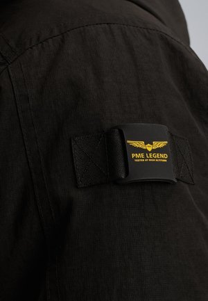 Textile noir avec une finition texturée, présentant une sangle noire avec une étiquette logo jaune indiquant "PME Legend" et un graphique d'aigle.