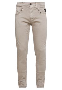 Vaqueros de mezclilla beige con corte ajustado, cinco bolsillos, detalle de costuras sutil y una etiqueta negra en el bolsillo trasero. Textura suave, acabado liso.
