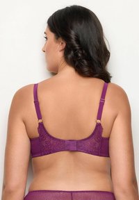 Lila spets-bh med justerbara remmar. Strukturerad mesh-tyg, knäppningar på baksidan, och intrikata spetssdetaljer vid axelbandet.