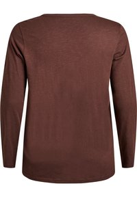 Rjava srajca z dolgimi rokavi in sproščenim krojem, z okroglim izrezom in gladko, lahko teksturo. Brez vzorcev ali izrazitih detajlov.