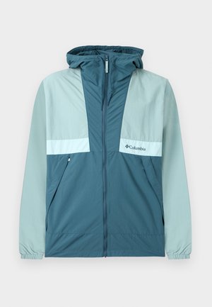 Sininen ja vaaleansinivihreä Columbia-hupparituulipuku, jossa on vetoketju edessä, sivutaskut ja joustavat hihansuut, esillä valkoisella taustalla.